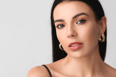 Işıklı arka planda güzel göz farları olan genç bir kadın.