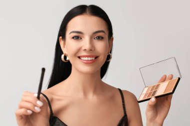 Işıklı arka planda güzel göz farları olan genç bir kadın.