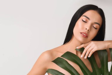 Güzel göz falı ve arka planda tropikal yaprağı olan genç bir kadın.