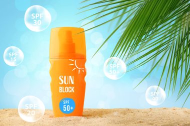 Bir şişe güneş koruyucu krem, tatil köyünde kumun üzerinde.