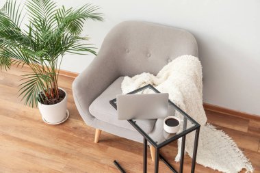 Laptoplu masa ve odada rahat bir koltuk.