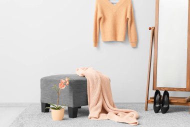 Pouf, giysileri ve aynası olan şık bir soyunma odası.