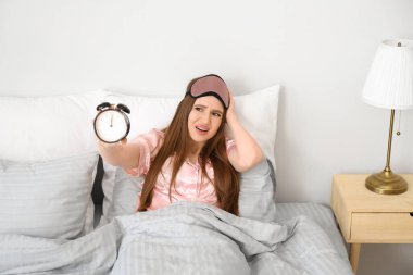 Çalar saati olan genç bir kadın yatak odasında uykusuzluk çekiyor.