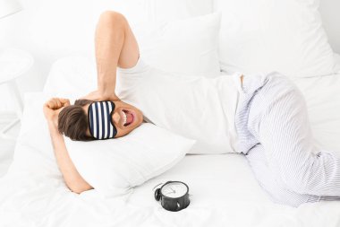 Çalar saati olan stresli adam yatak odasında uykusuzluk çekiyor.
