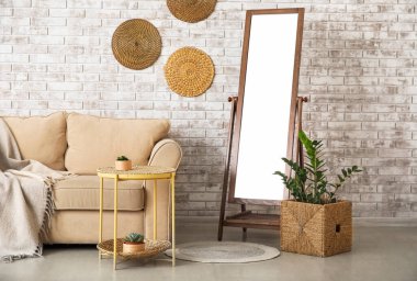 Odasında tuğla duvarın yanında kanepesi olan büyük ayna.