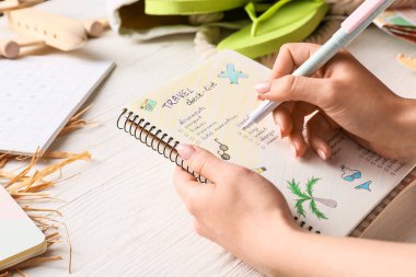 Seyahat için toplanacak eşyaların listesini hazırlayan kadın