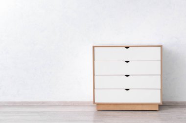 Çekmecelerin modern sandığı, odanın ışık duvarının yanında.