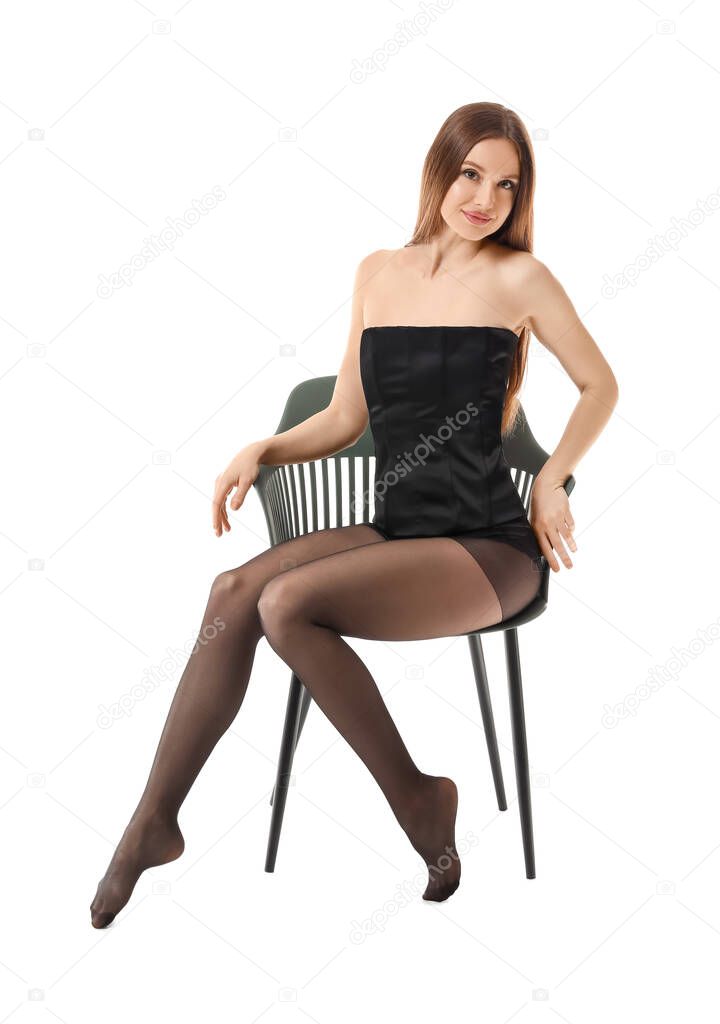 Beautiful young woman in tights sitting on chair against white background