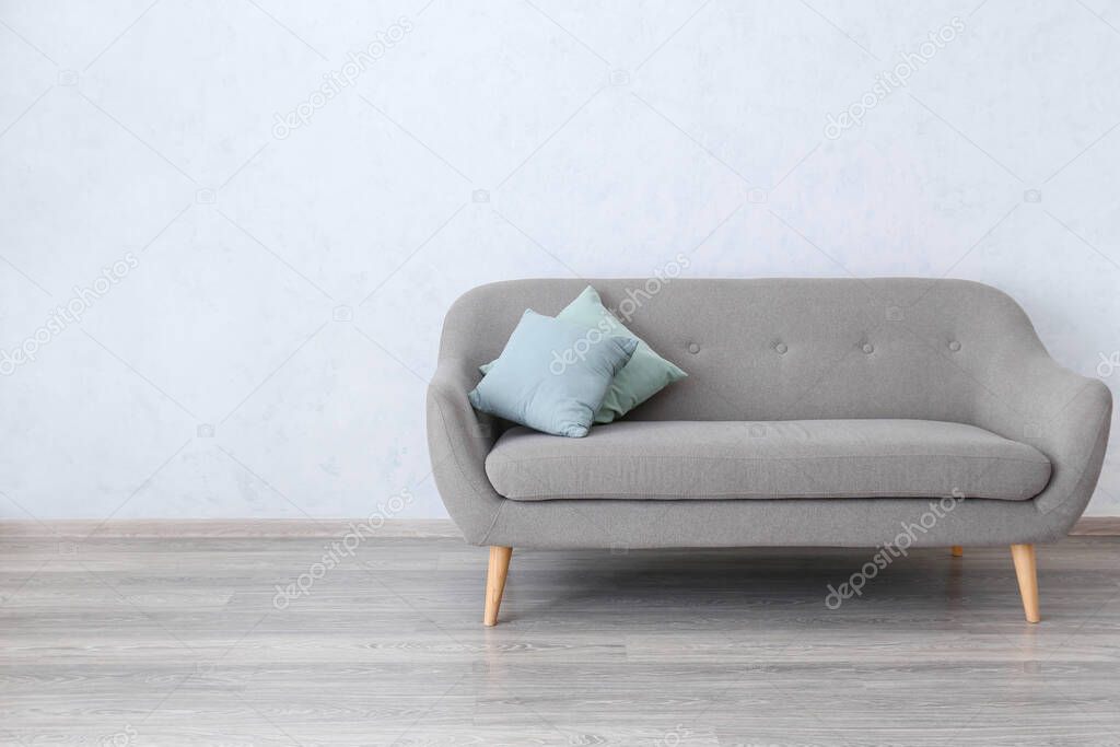 Stylish sofa near white wall