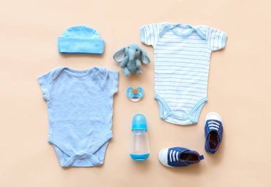 Şişeli bebek kıyafetleri, emzik ve arka planda oyuncak