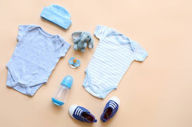 Şişeli bebek kıyafetleri, emzik ve arka planda oyuncak