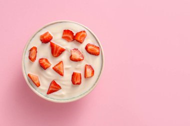 Arka planda bir kase çilekli yoğurt.