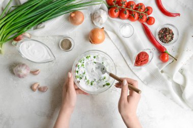 Kadın arka planda leziz bir sos hazırlıyor.