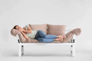 Genç kadın arka planda modern kanepede uyuyor.