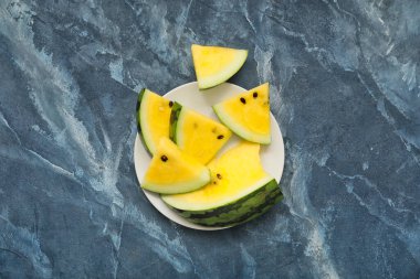 Masada kesilmiş sarı karpuz tabağı.