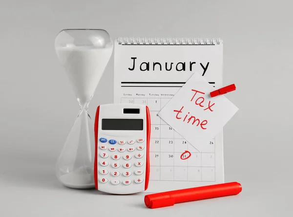 Hourglass with calculator and calendar on light background. Concept of tax deadline