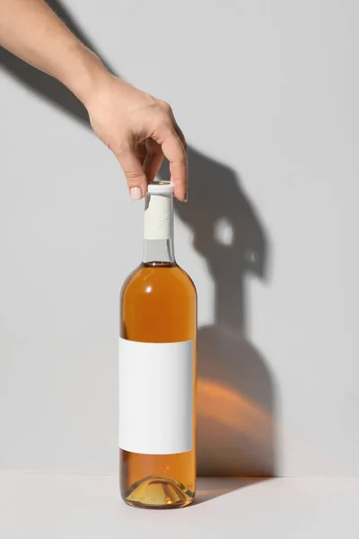 Mano Botella Vino Con Etiqueta Blanco Sobre Fondo Claro — Foto de Stock