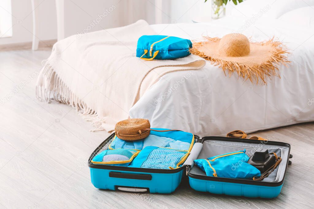 Suitcase and set of travel organizers with belongings at home