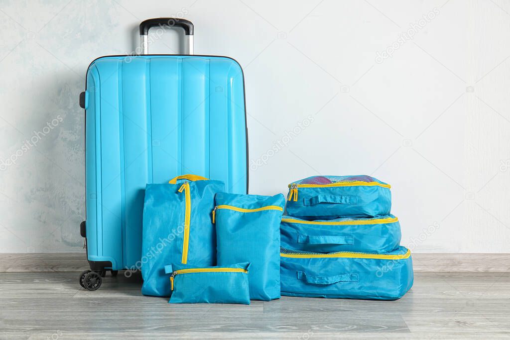 Suitcase and set of travel organizers with belongings on floor