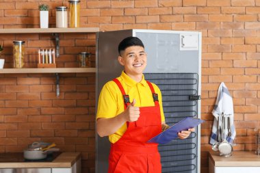 Mutfaktaki buzdolabını tamir eden bir işçi.