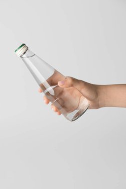 Arka planda temiz su şişesi olan bir el.