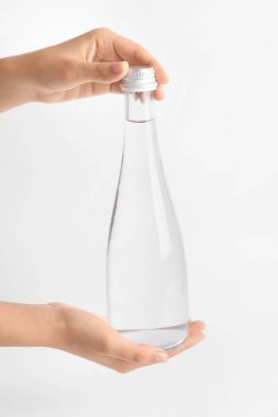 Açık arkaplanda temiz su şişesi olan eller.