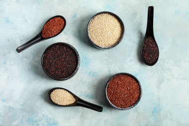 Renkli arka planda farklı kinoalı kase ve kaşıklar