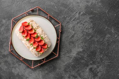 Koyu arkaplanda çilekli lezzetli kremalı pasta.