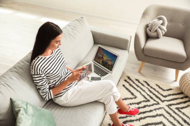 Tablet bilgisayarı olan bir kadın evinde online bilet ayırtıyor.