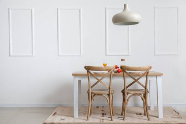 Beyaz duvarın yanındaki yemek masasında.