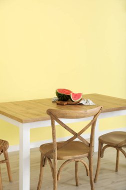 Renk duvarının yanında karpuz olan yemek masası.