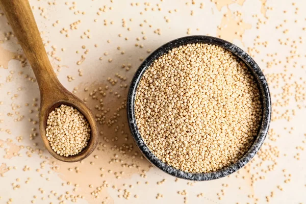 Beyaz arka planda sağlıklı kinoalı kase ve kaşık.