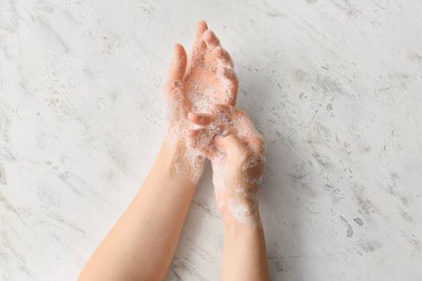 Genç bir kadın arka planda ellerini yıkıyor.