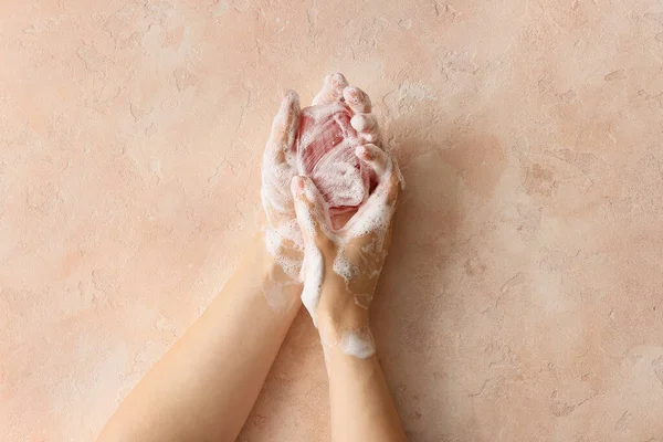 Ellerini renkli arka planda yıkayan genç bir kadın.