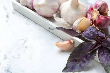 Taze sarımsaklı tabak ve arka planda fesleğen.