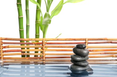 Beyaz zemin üzerinde suyla kaplıca taşı ve bambu yığını