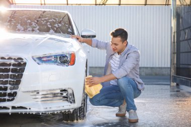 Adam dışarıda arabasını yıkıyor.
