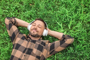 Yakışıklı adam parkta dinlenirken müzik dinliyor.