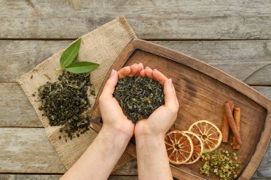 Ahşap arka planda kuru çay yaprakları olan kadın eller.