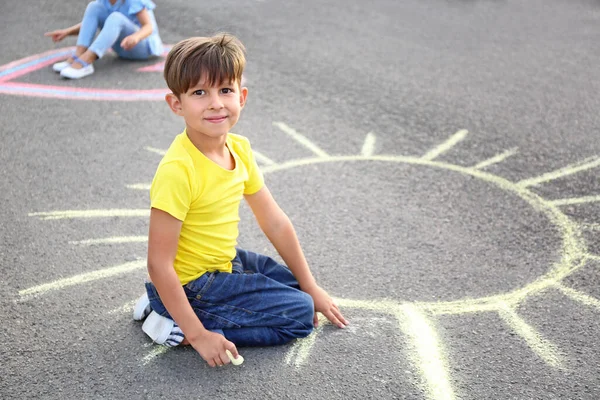 アスファルトの上にチョークで太陽を描く小さな男の子 — ストック写真