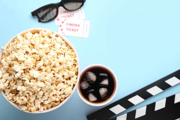 Popcorn, 3D glasses, cola, movie clapper and cinema tickets on color background