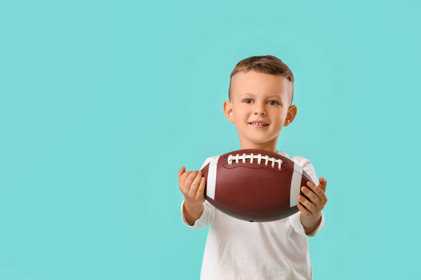 Little boy with rugby ball on color background