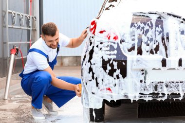 Erkek işçi dışarıda araba yıkıyor.