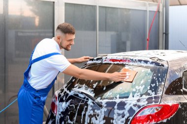 Erkek işçi dışarıda araba yıkıyor.