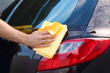 Erkek işçi dışarıda araba yıkıyor.