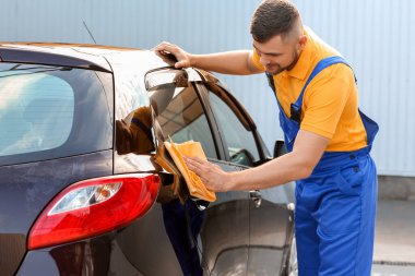 Erkek işçi dışarıda araba yıkıyor.