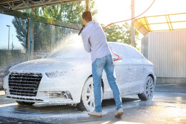 Adam dışarıda arabasını yıkıyor.