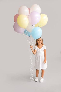 Gri arka planda balonları olan küçük kız.