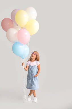 Gri arka planda balonları olan küçük kız.