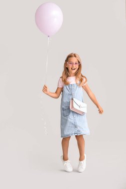 Gri arka planda balonu olan küçük kız.